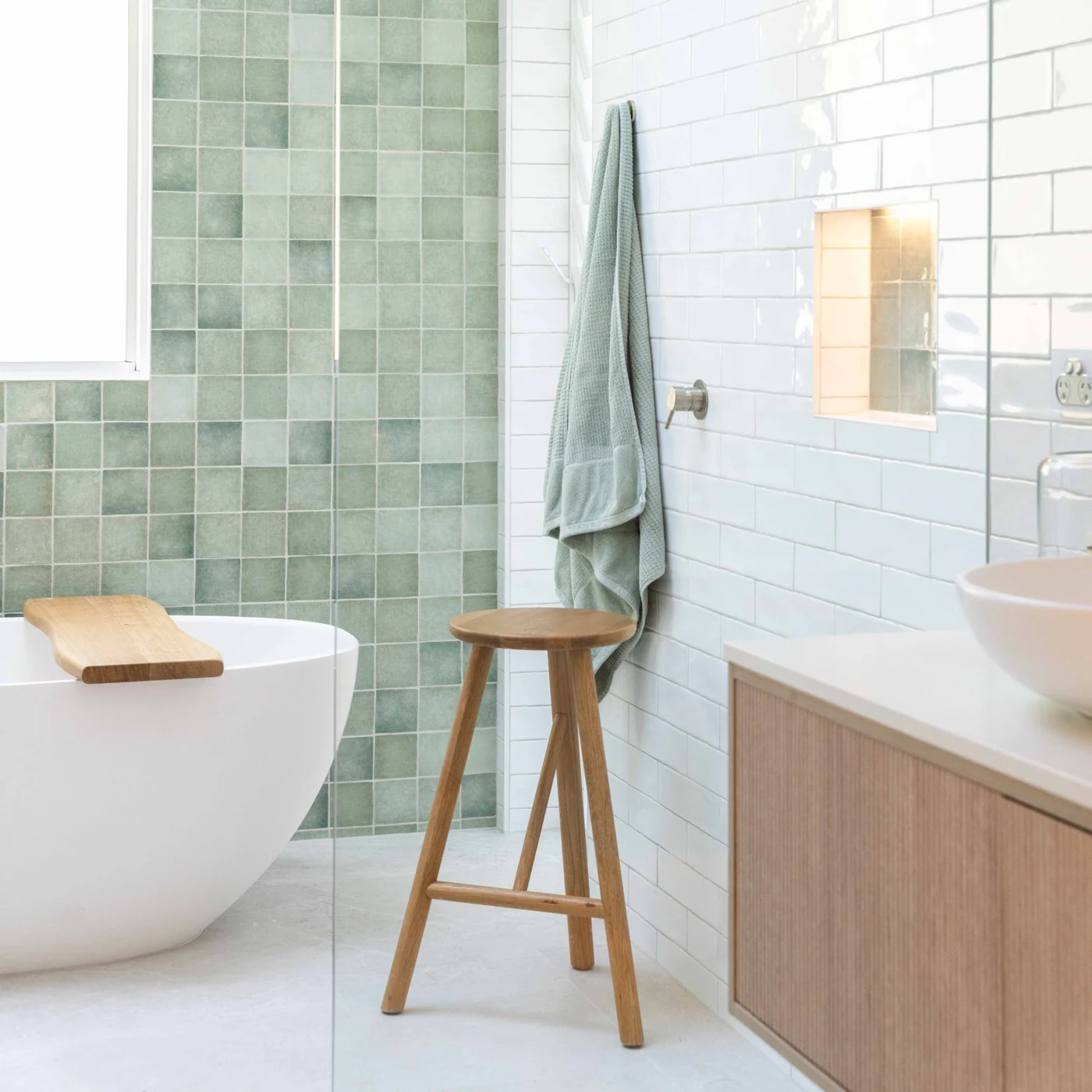 Bathroom with sage green square tiles, white gloss wall tiles, a rain shower, a freestanding bath and a timber stool