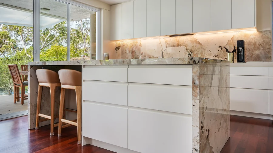 Open-plan kitchen at Balmoral, stone waterfall island and white joinery over red timber floors