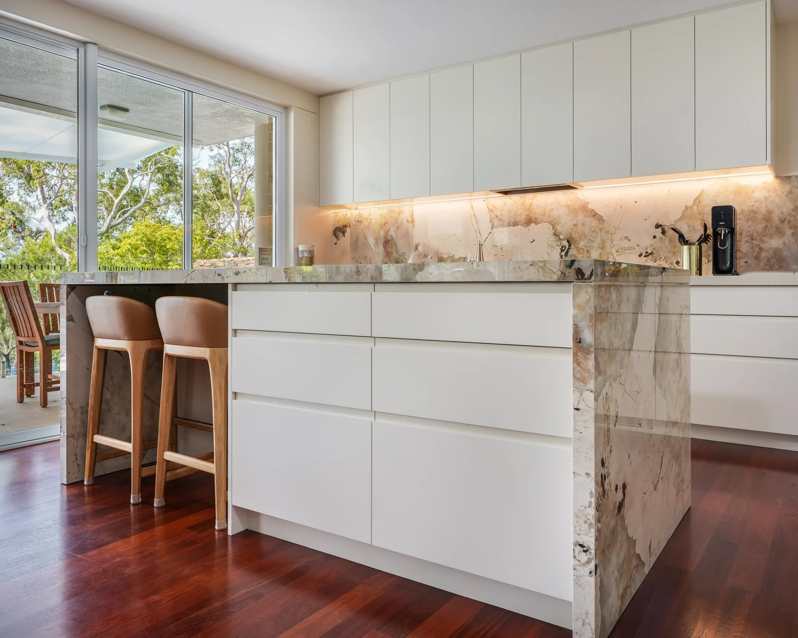Open-plan kitchen at Balmoral, quartzite island and splashback with the bushland beyond