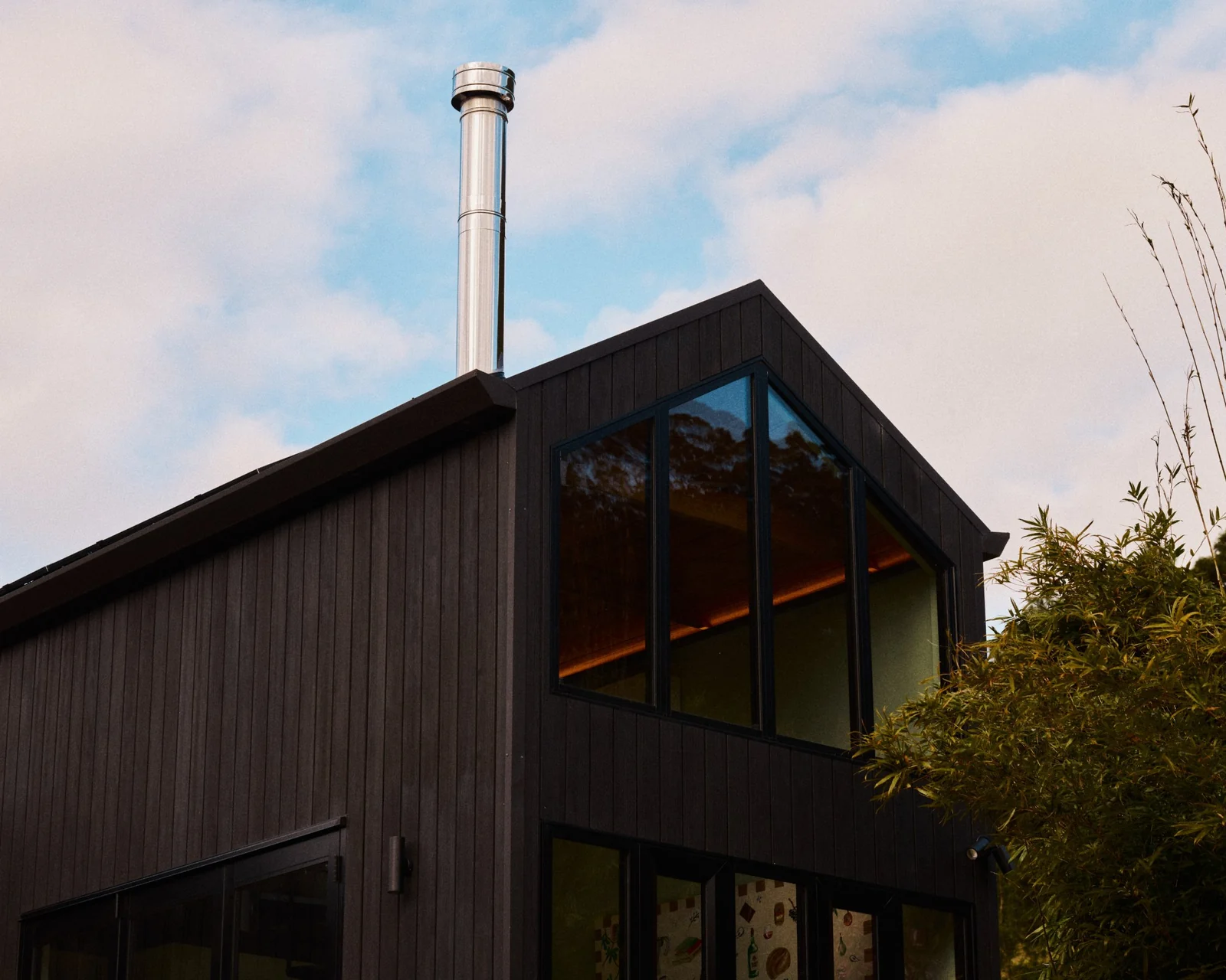 Amity-built cabin: dark vertical-board cladding, a raked gable window and a stainless steel flue