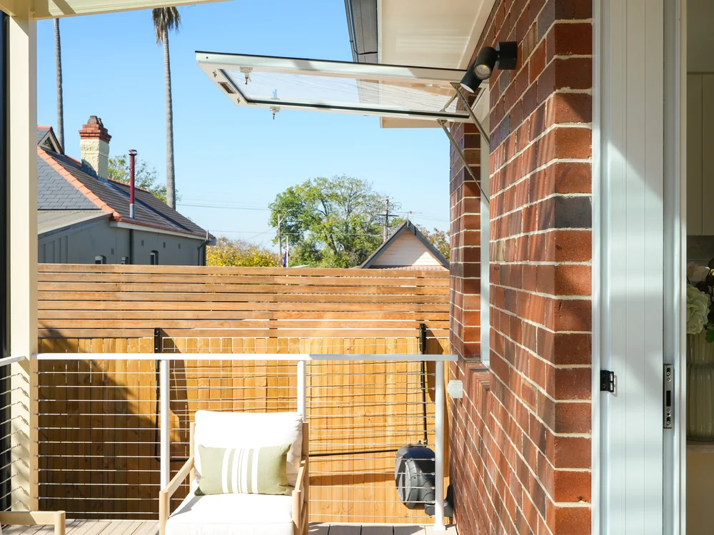 Rear deck with an awning window opening from the kitchen to the brick wall beyond