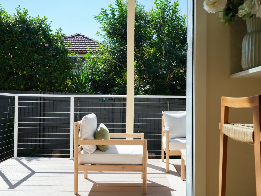 Timber lounge chairs on the rear deck, screened by planting