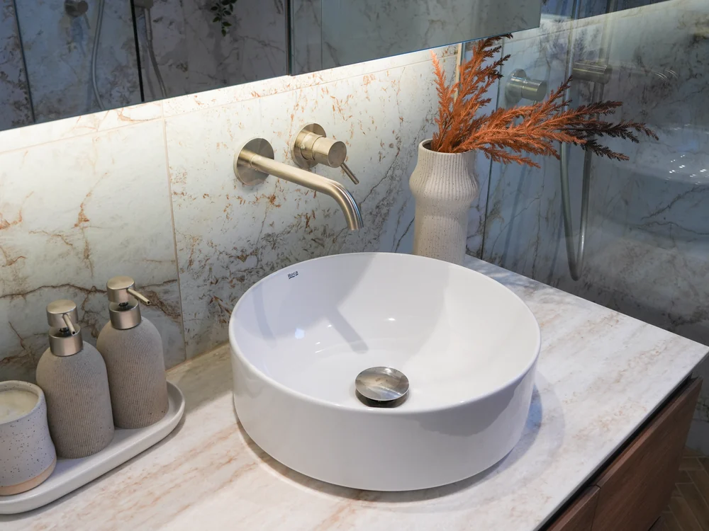Bathroom vanity with a round basin and wall-mounted tapware