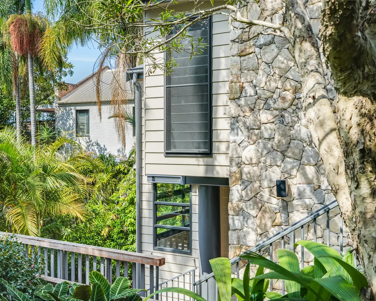 The Mosman studio from the garden, weatherboard cladding meeting a hand-placed stone wall